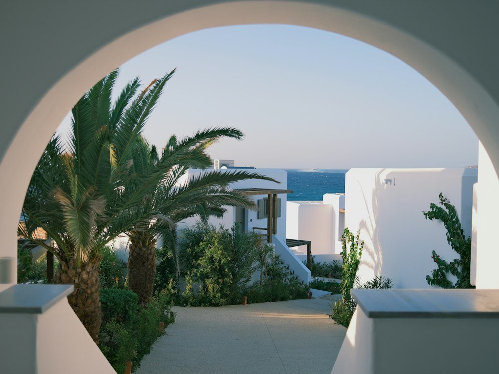 A whitewashed arched terrace framing palms and sea